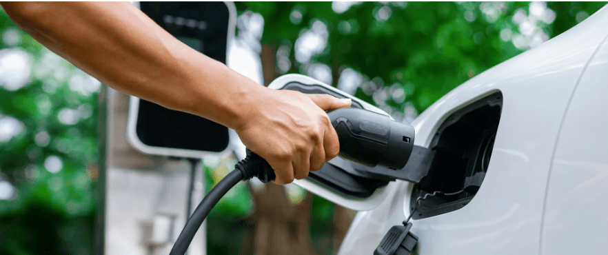 Driver plugging a charging connector into a white electric car